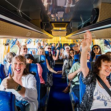 Group on tour bus smiling with thumbs up